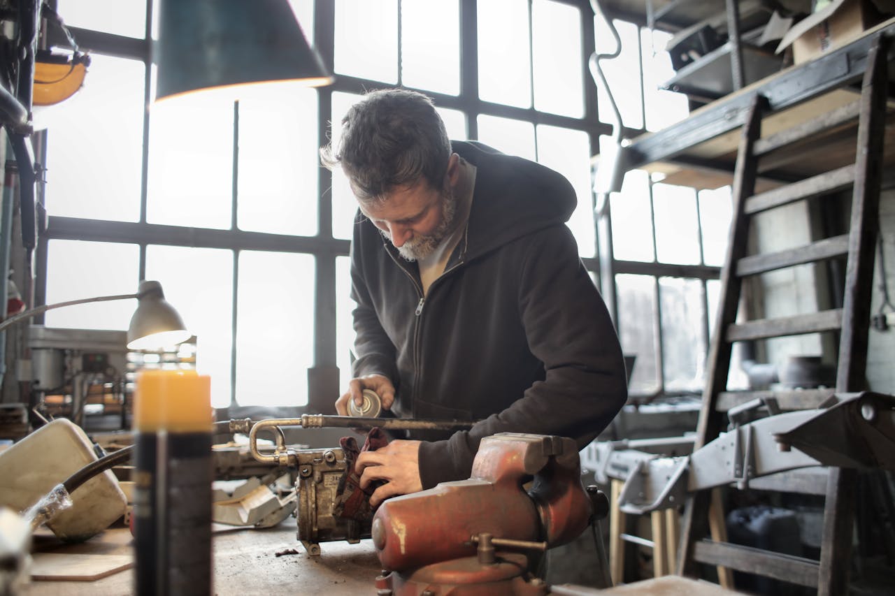 Focused male mechanic using spray paint on metal detail in a workshop