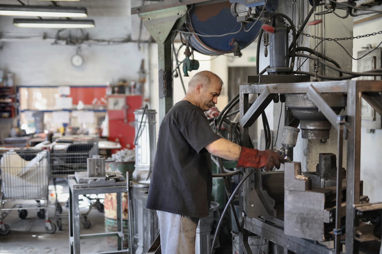 Elderly white hair worker using machine in a workshop