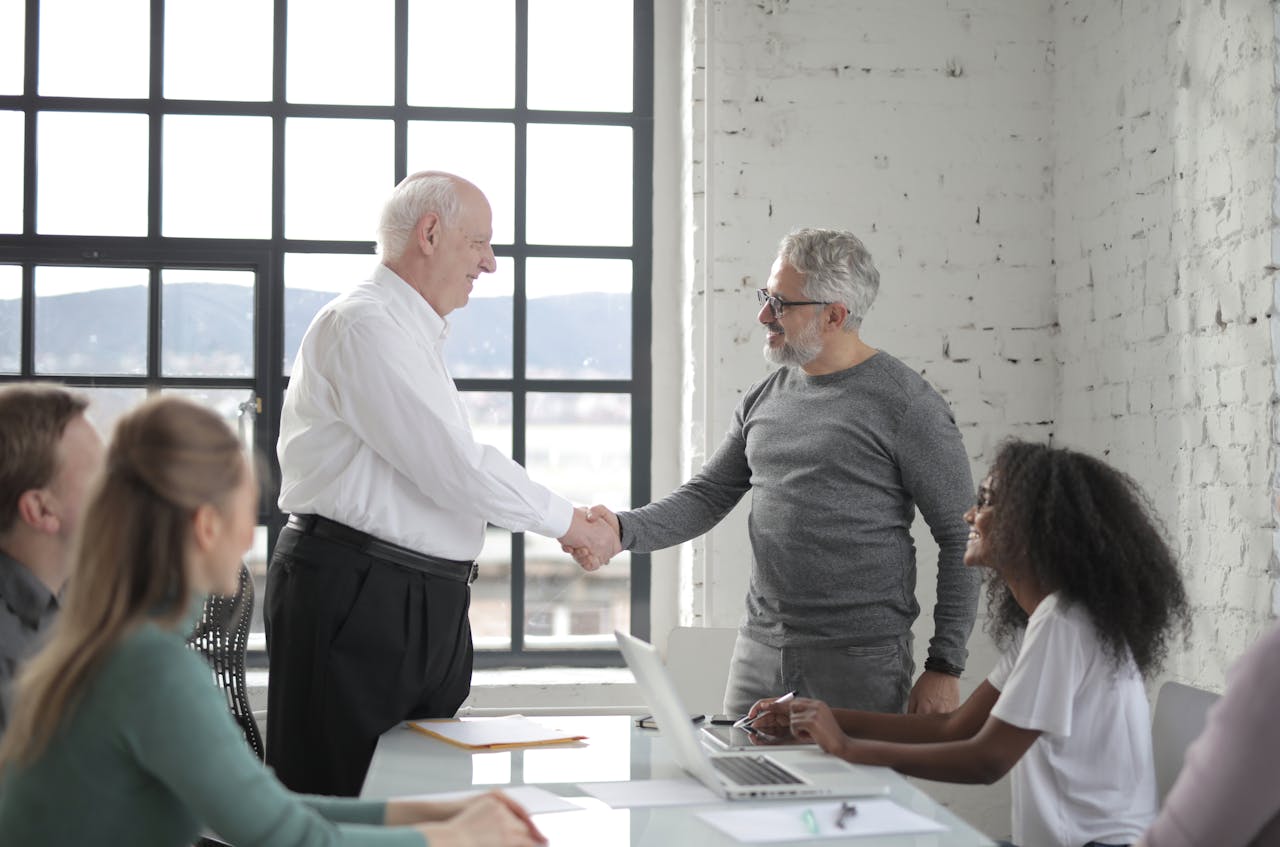 Cheerful different ages colleagues shacking hands in office