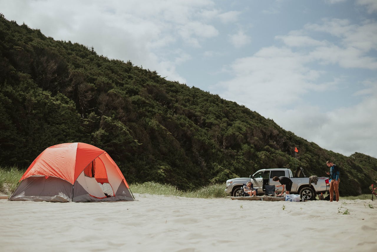 Campers near a van and tent on sandy beach