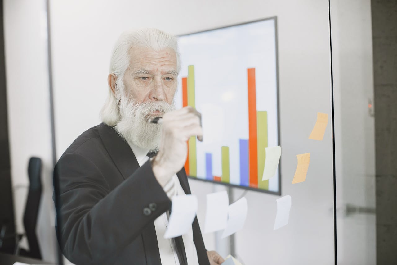 Photo of an elderly man in office holding a pen in black suit