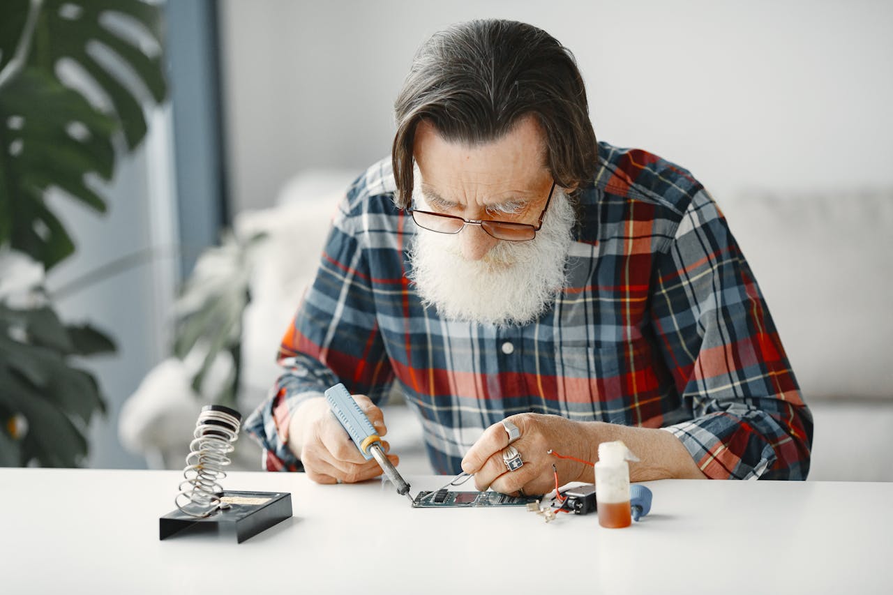 Close up shot of a bearded man in checkered long sleeve using electronic equipment