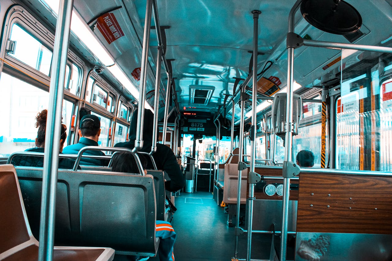 Photo of bus interior, people sitting on bus bench seats.
