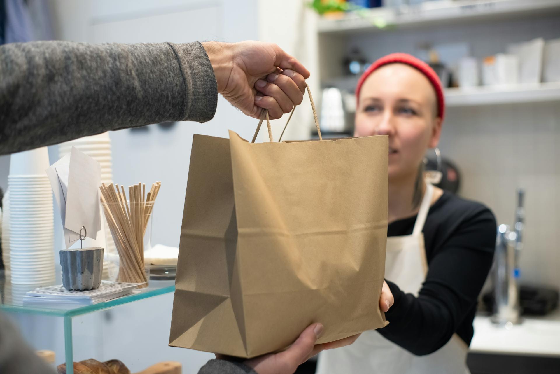 Close up of restaurant worker handing a bag with takeaway food to a client
