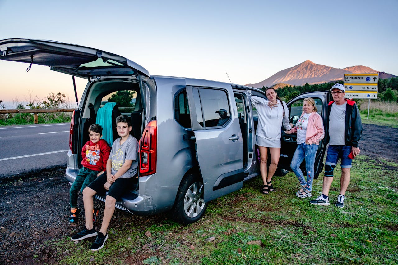 Photo of a smiling family standing next to a van