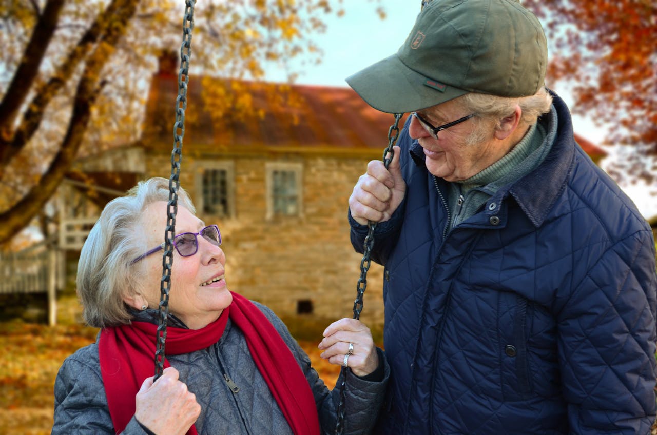 Man standing beside woman on swing looking at each other