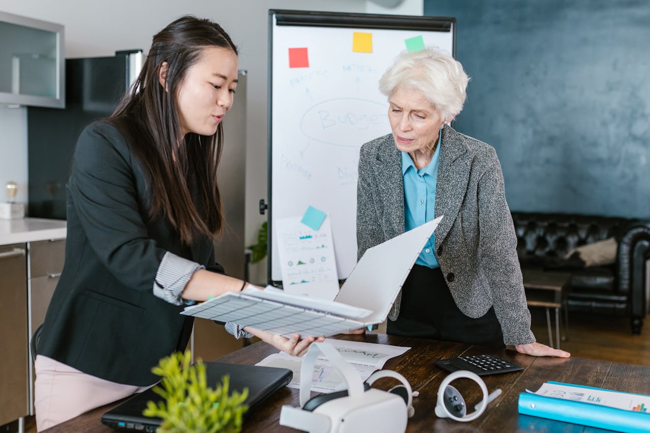 Two businesswomen working together in an office standing next to each other and having a conversation