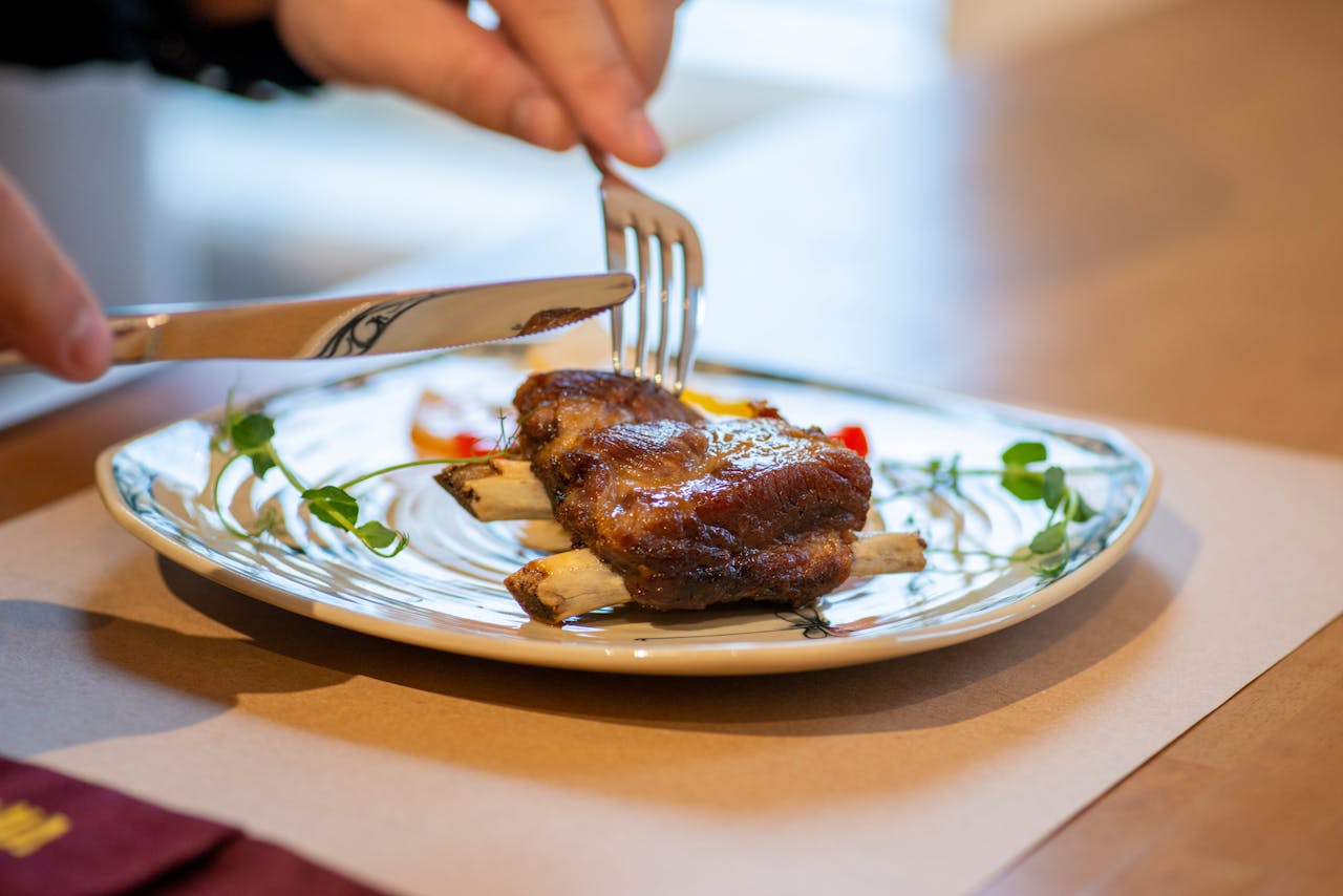 Close up of person eating meat with knife and fork