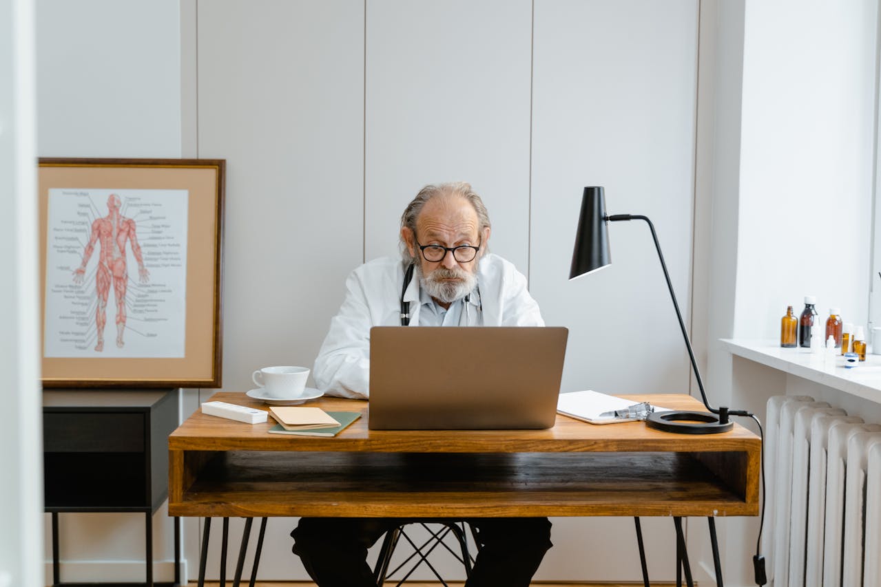 An elderly man working on his laptop sitting on office desk