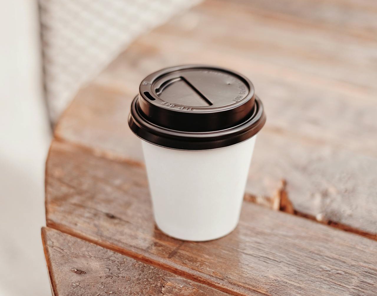 Close-up-photo of disposable coffee cup on wooden table top