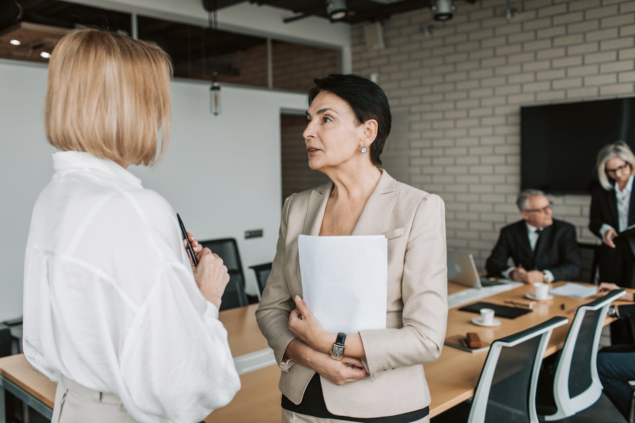 Two women standing next to each other and having a conversation in an office