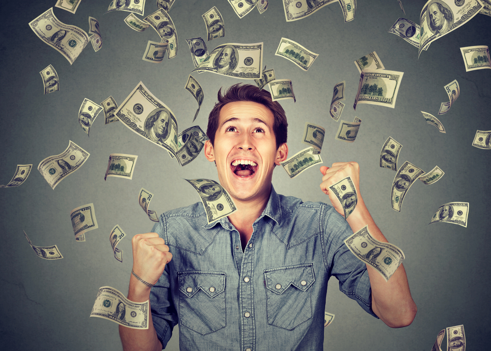 Teen boy smiling under money rain
