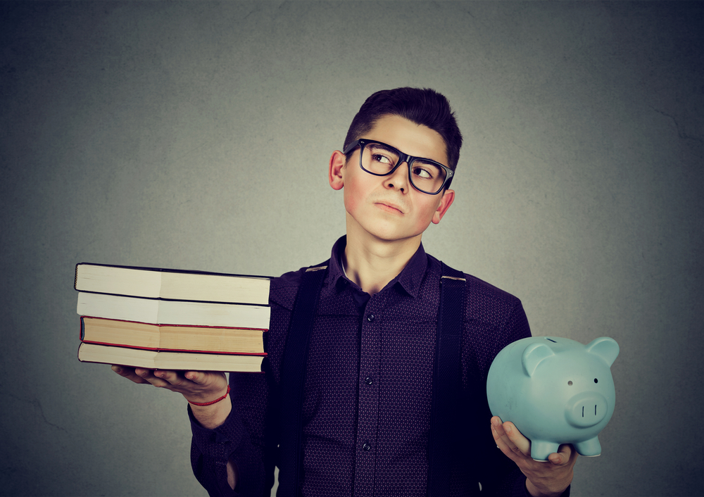 Teen holding piggy bank and books