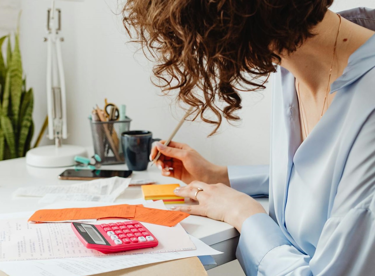 Woman in Blue Long Sleeve Shirt Writing on Orange Paper