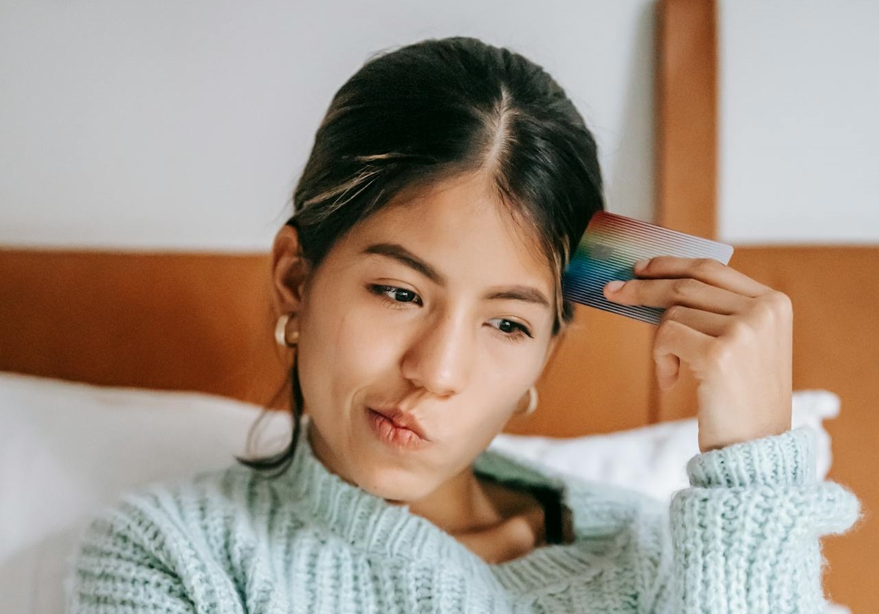 Woman with debit card and laptop on bed.