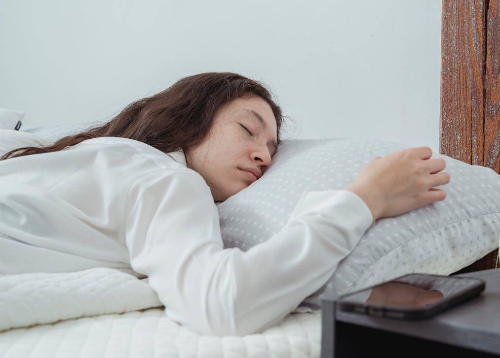 Young female sleeping on bed in morning