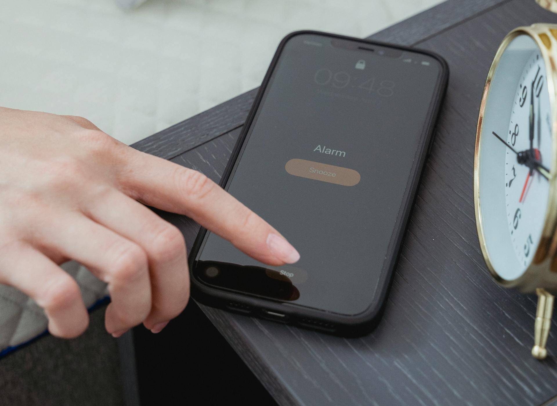 Crop woman snoozing alarm on smartphone