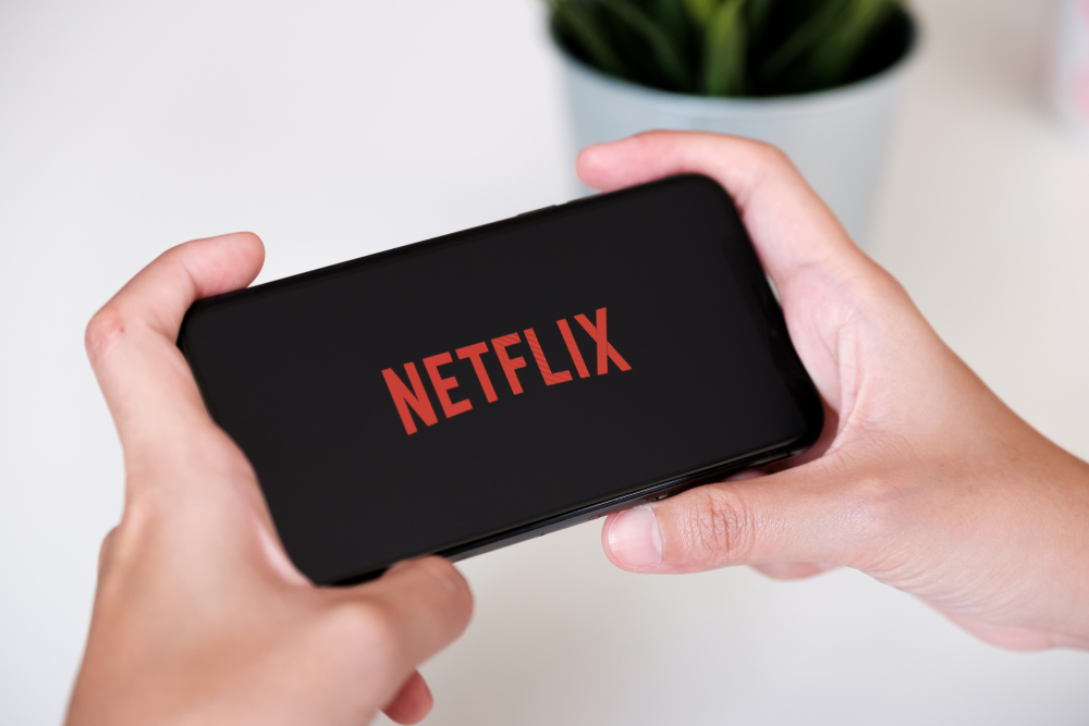 Woman hand holding Smart Phone with Netflix logo