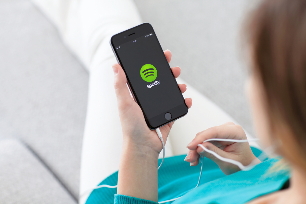 Woman holding a phone with music service Spotify