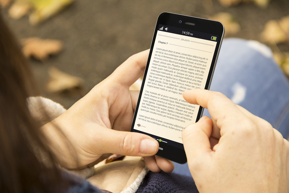 young woman reading a book on a phone screen
