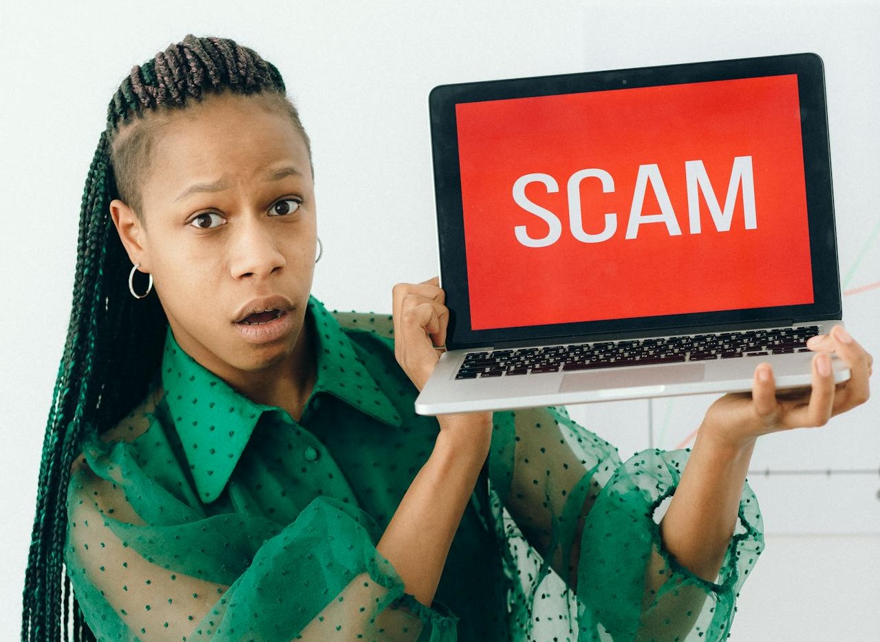 A Shocked Woman Holding a Laptop with SCAM sign.