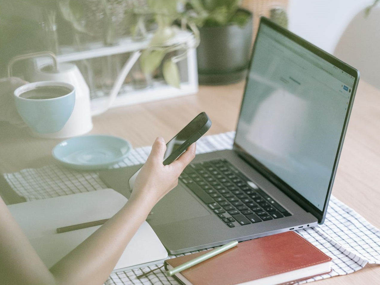 Crop faceless woman using on laptop and smartphone at home