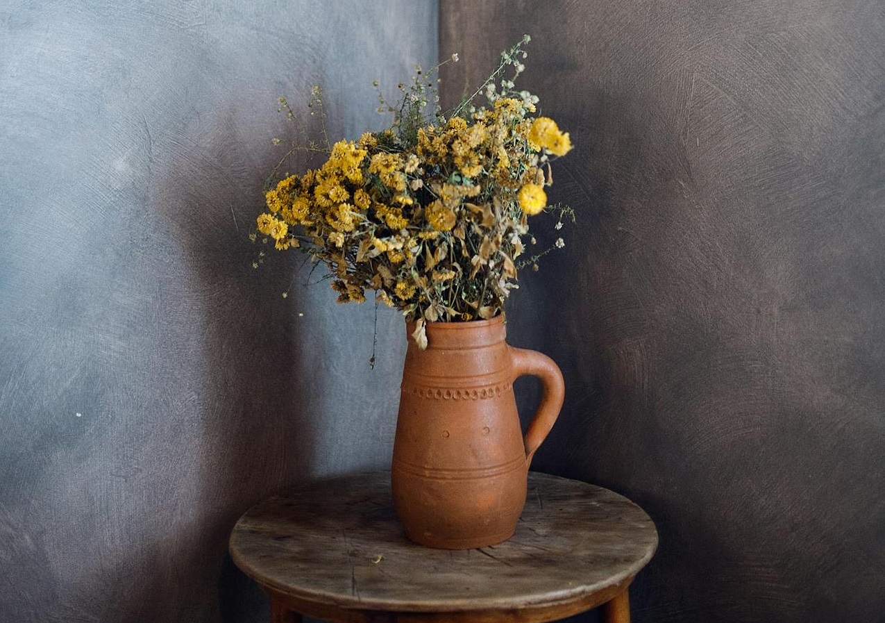 Wild flowers in vase in dark room.