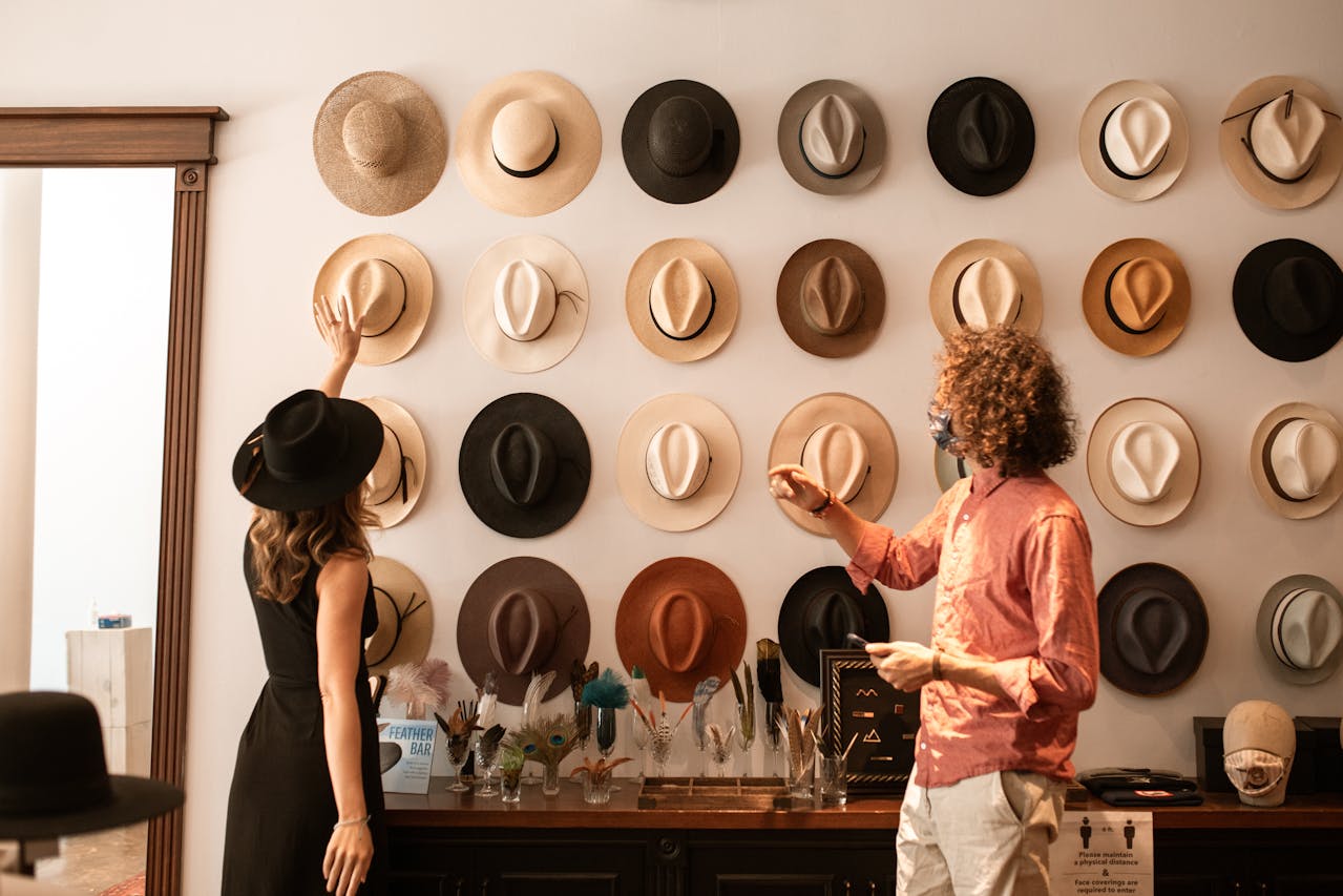 A Woman Looking at Fedora Hats Hanging on the Wall