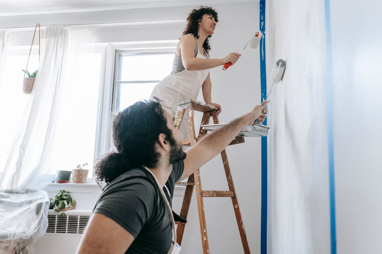Couple Painting A Wall at home.