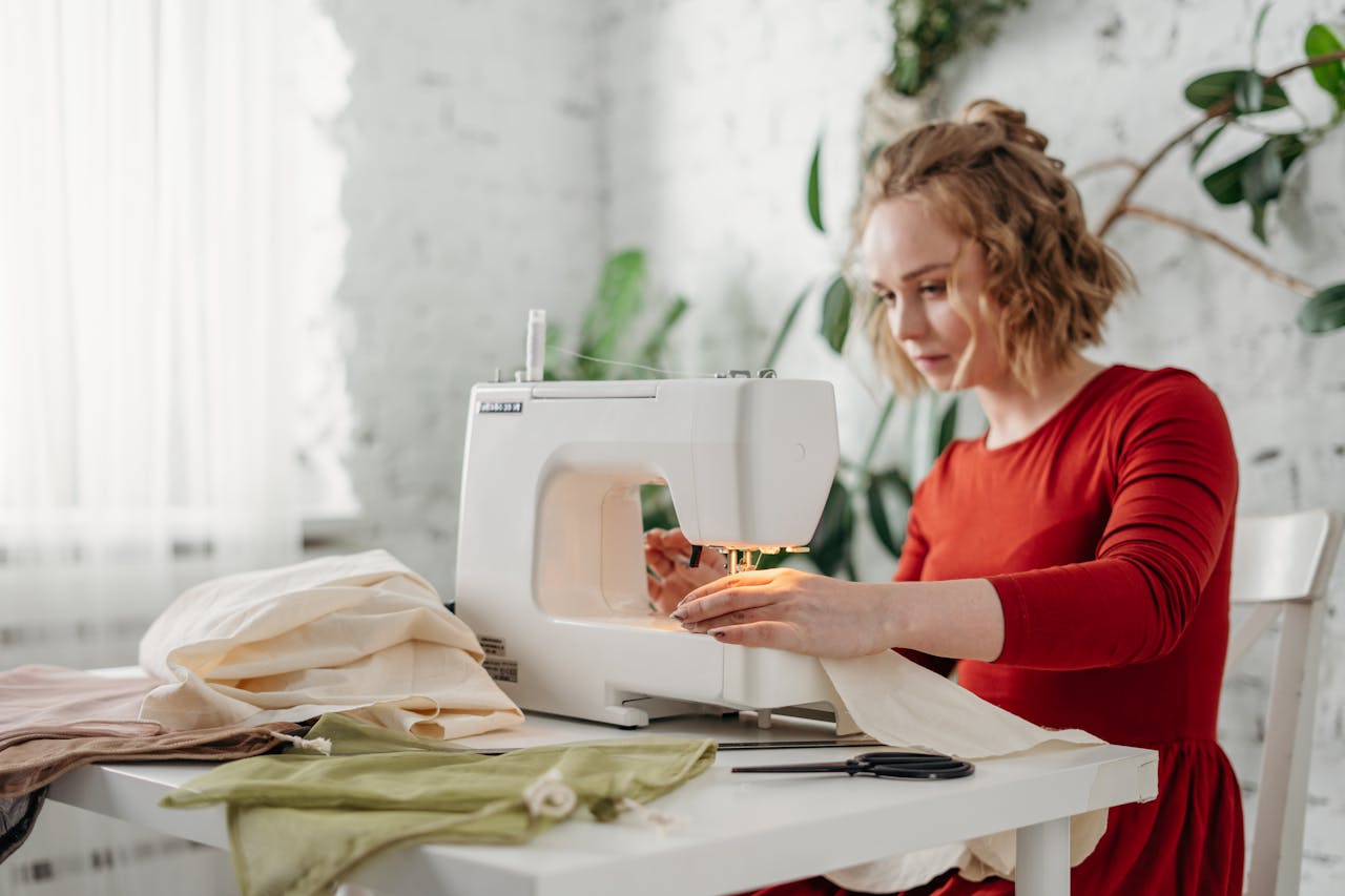 Portrait Photo of Woman in red dress Sewing While Sitting on Chair