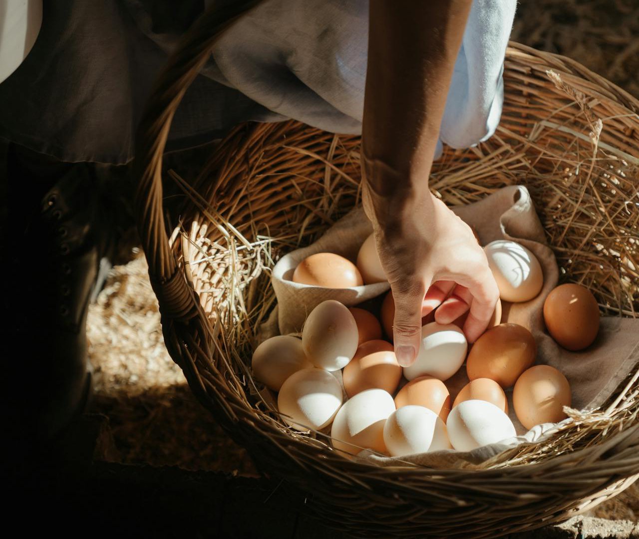 Close Up Photo of a Person picking up egg from a basket