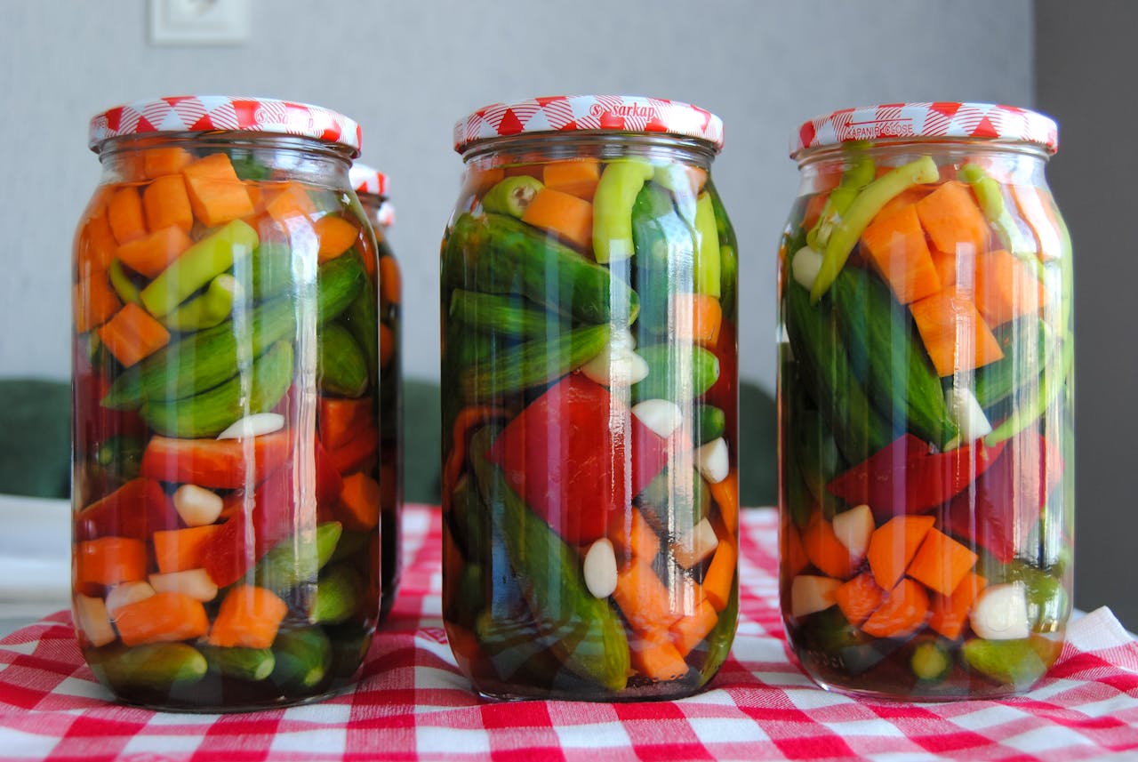 Close Up Photo of Preserved Vegetables in Jars placed on a table