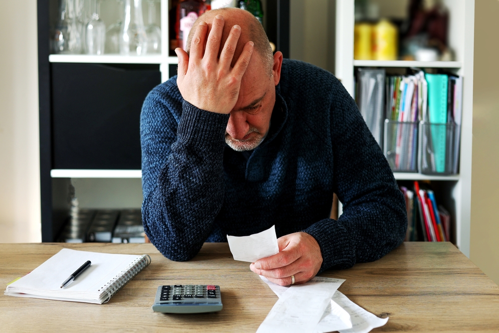 Man upset sitting on a table holding his head
