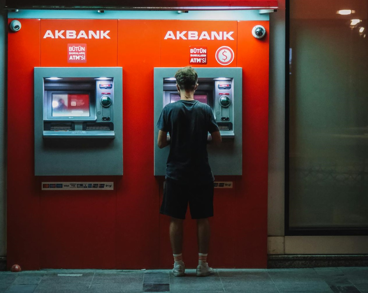 Man Standing in Front of a Red ATM