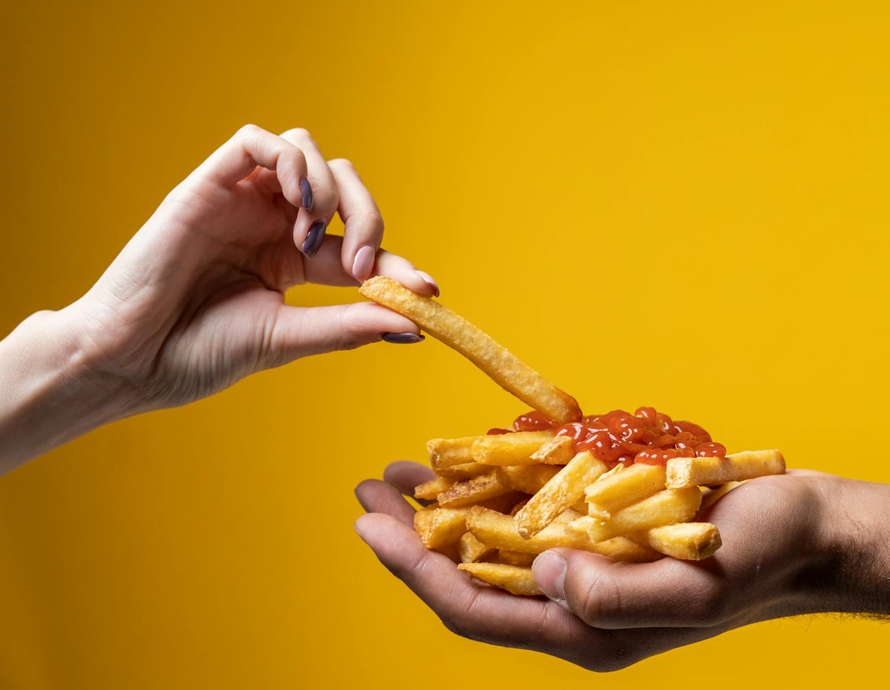 Person Sharing French Fries on yellow background.