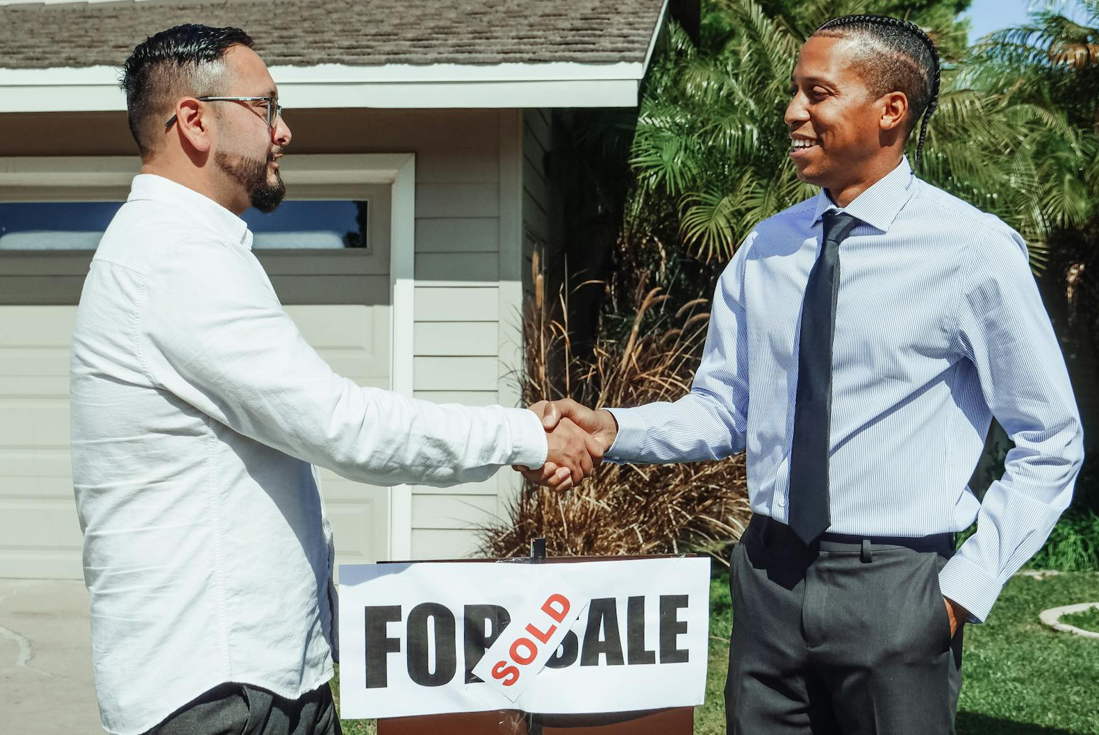 Men Shaking Hands in front of a sign
