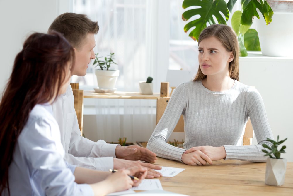 Three millennial people sitting at the desk in office boardroom