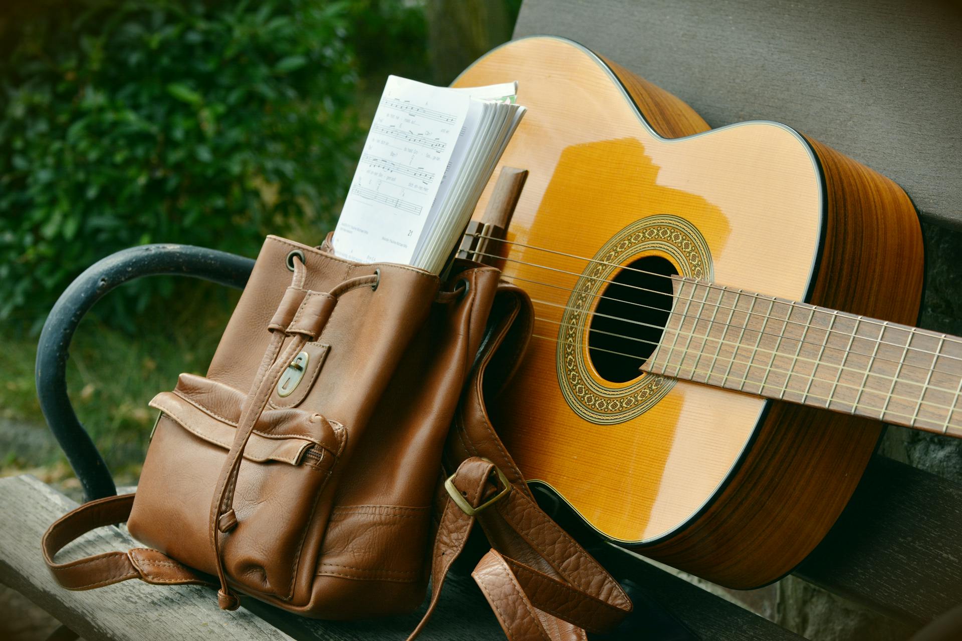 Brown Acoustic Guitar Beside Brown Leather Backpack