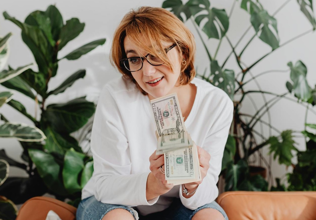 Woman Holding Paper Money while Sitting on a Couch