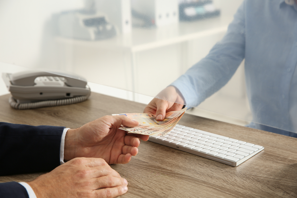 Man receiving money from teller at cash department