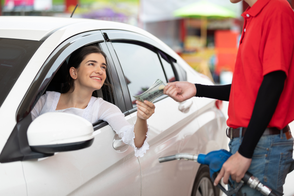 customer paying in cash to worker after refueling a vehicle at gas station