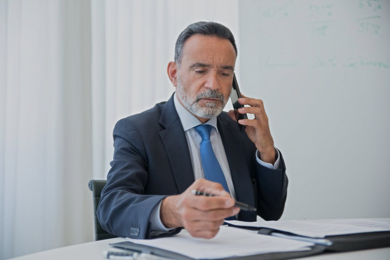 A Man in Black Suit Talking on the Phone