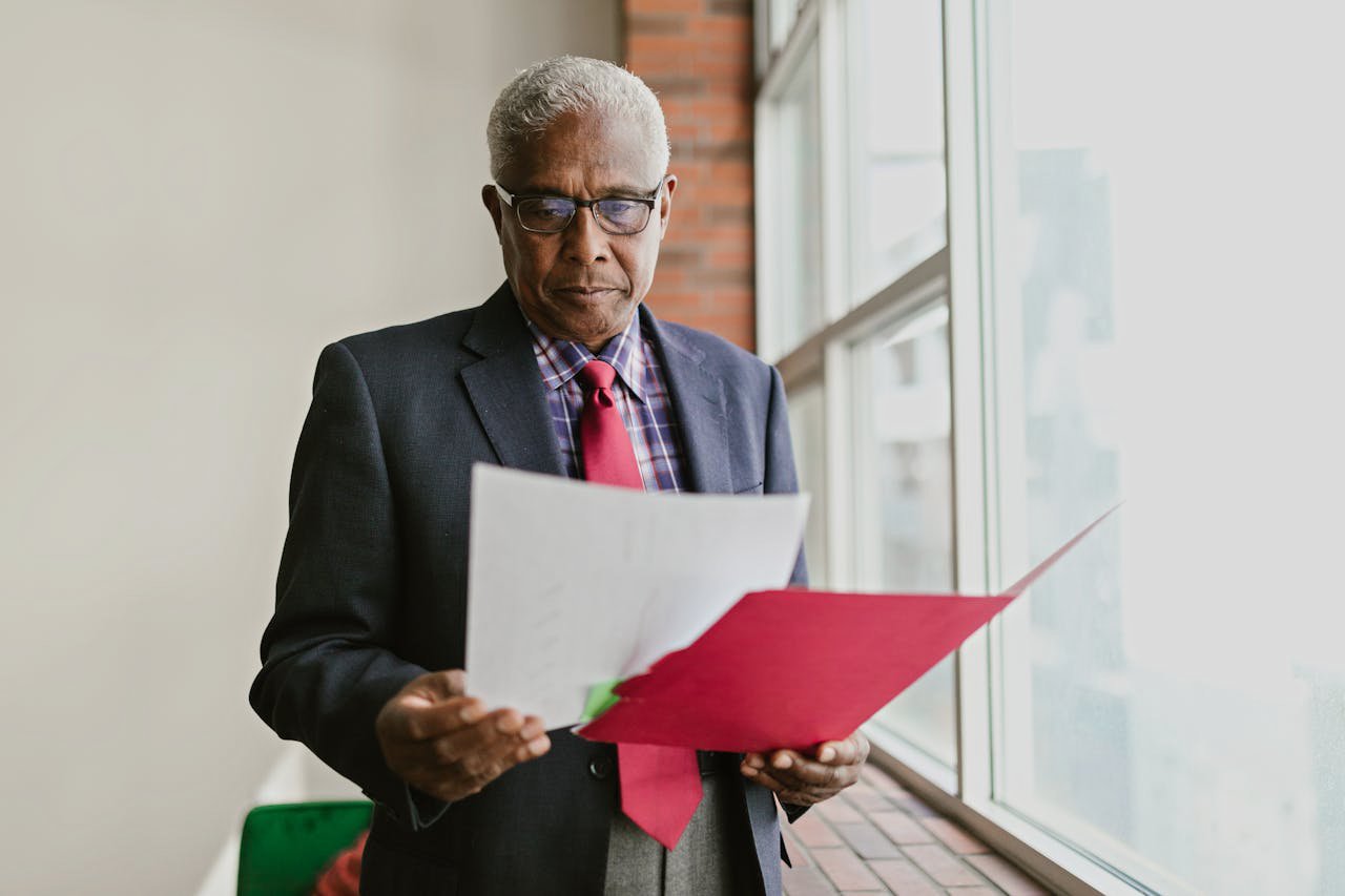 A Man in a Black Suit Holding a White Paper