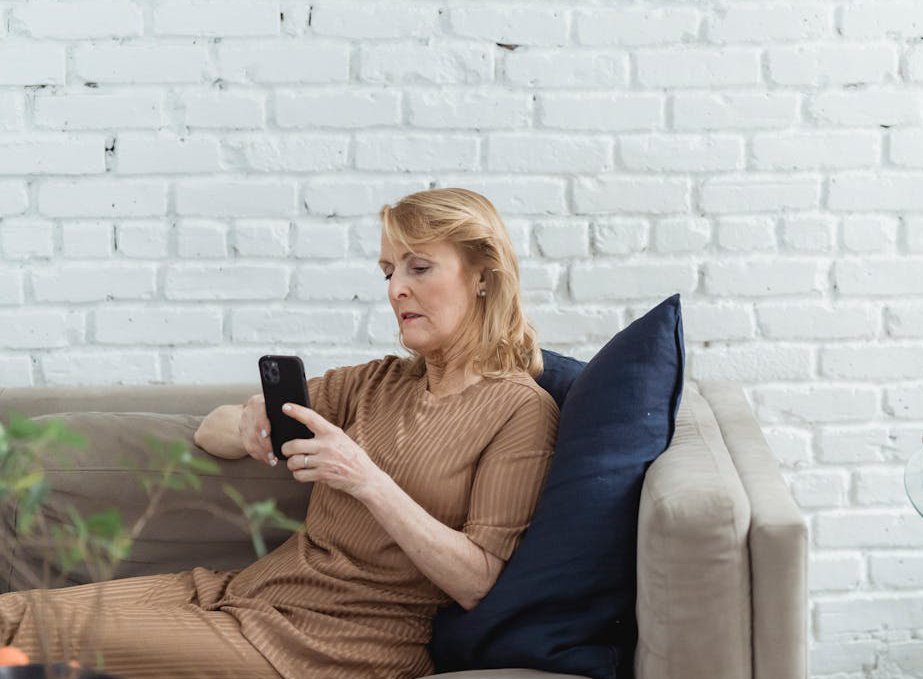 Elderly woman chatting on smartphone on sofa