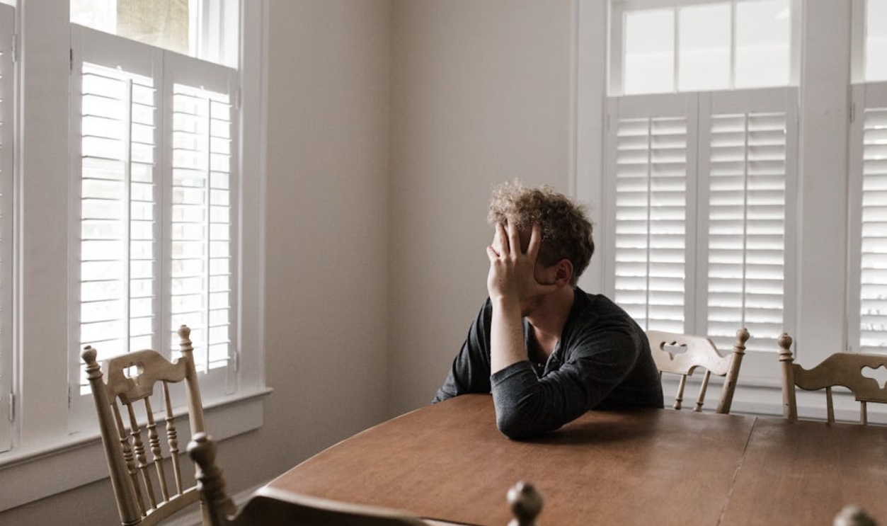 /photo-of-man-leaning-on-wooden-table