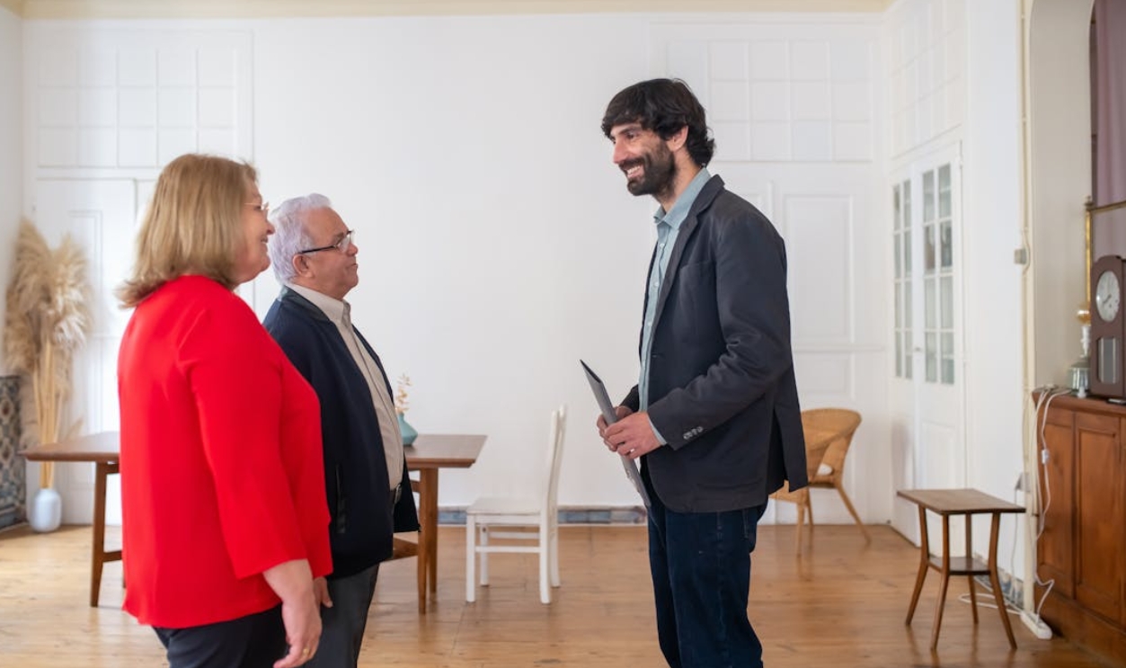 /man-in-gray-blazer-talking-in-front-of-elderly-couple