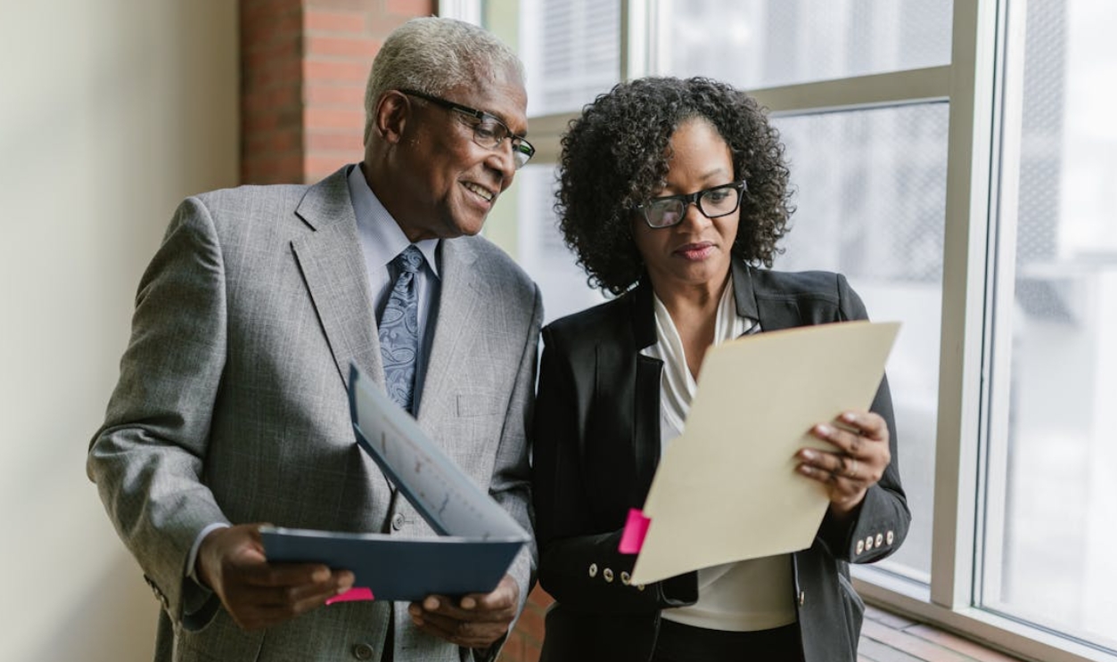 /an-elderly-man-and-a-woman-looking-at-the-folder-while-having-a-conversation