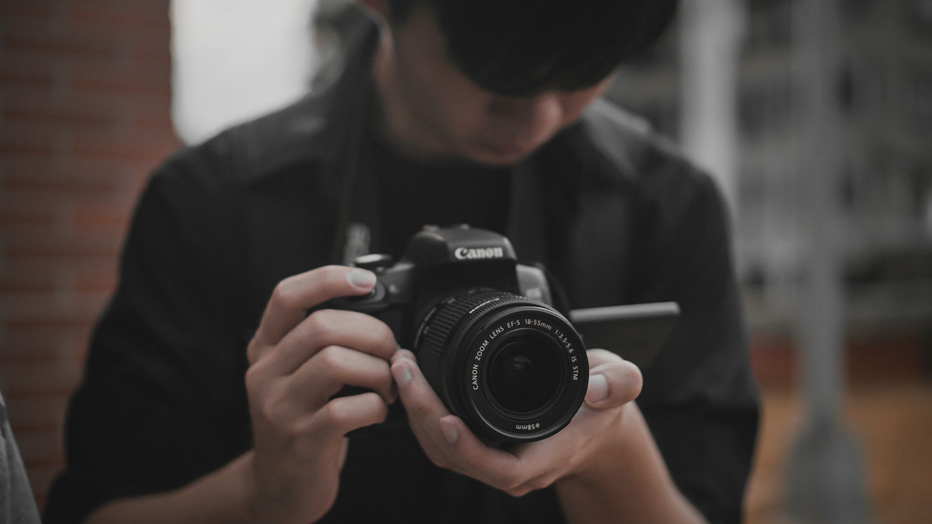 man in black shirt holding black nikon dslr camera