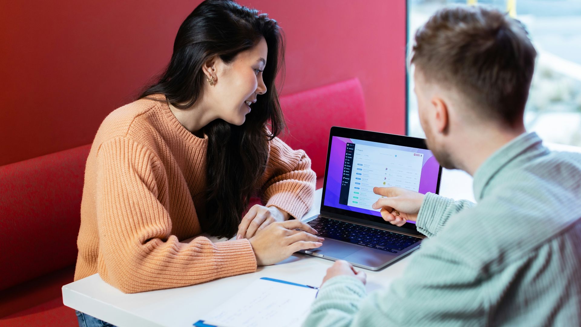a man and a woman sitting at a table with a laptop