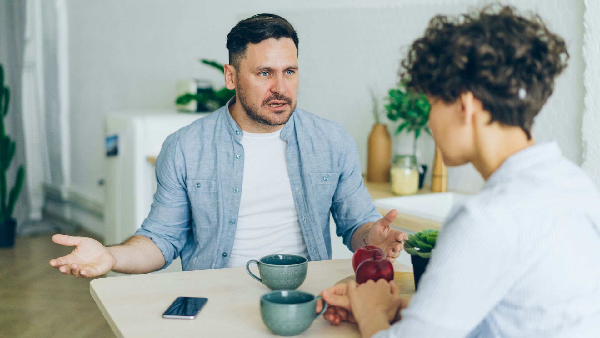 a man sitting at a table talking to a woman